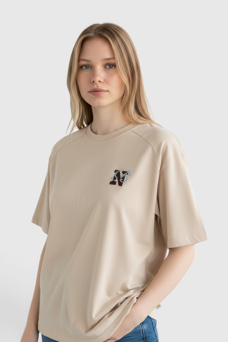 Sporline New Balance bej renkli, %100 pamuklu, regular kesim unisex tişört giyen sarışın model