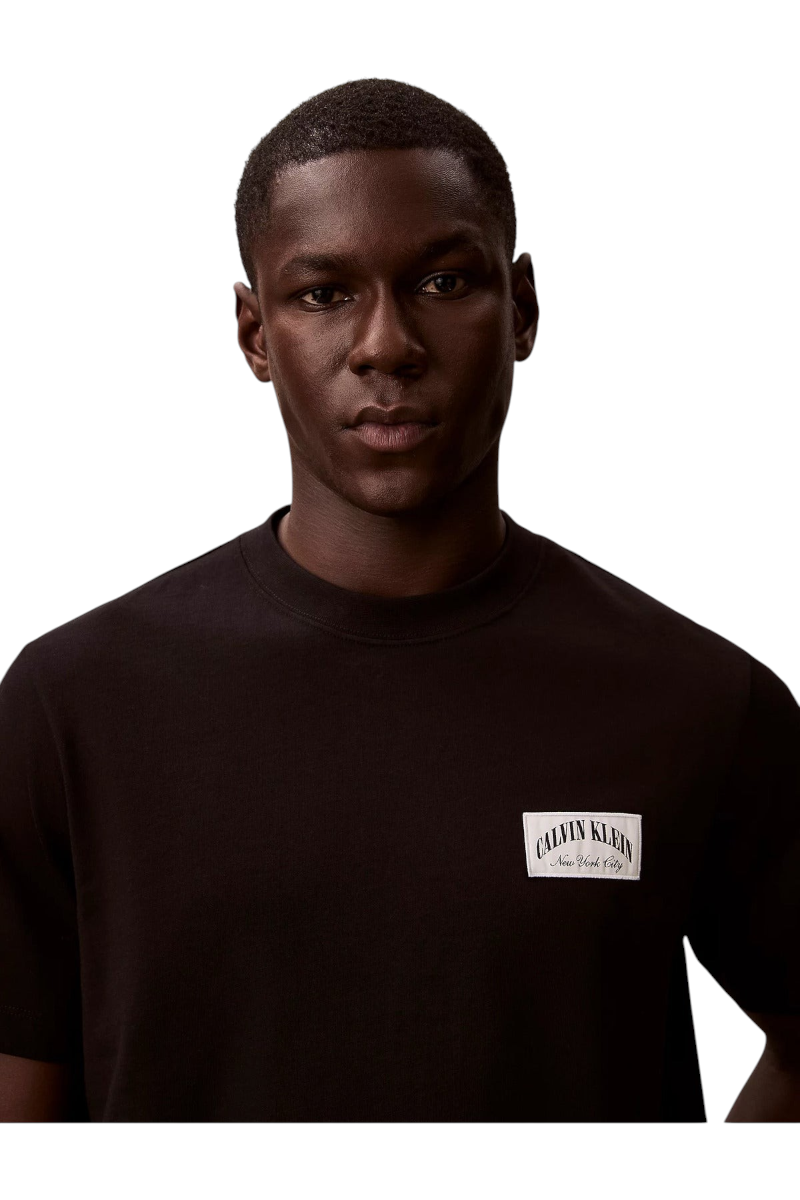 Sporline Calvin Klein siyah comfort kesim erkek tişört, göğüs kısmında beyaz marka logolu yama detayı ile.
