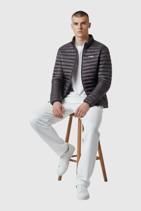 Sporline Lumberjack ML Perry siyah polyester erkek şişme mont giyen bir model stüdyo ortamında taburede oturuyor