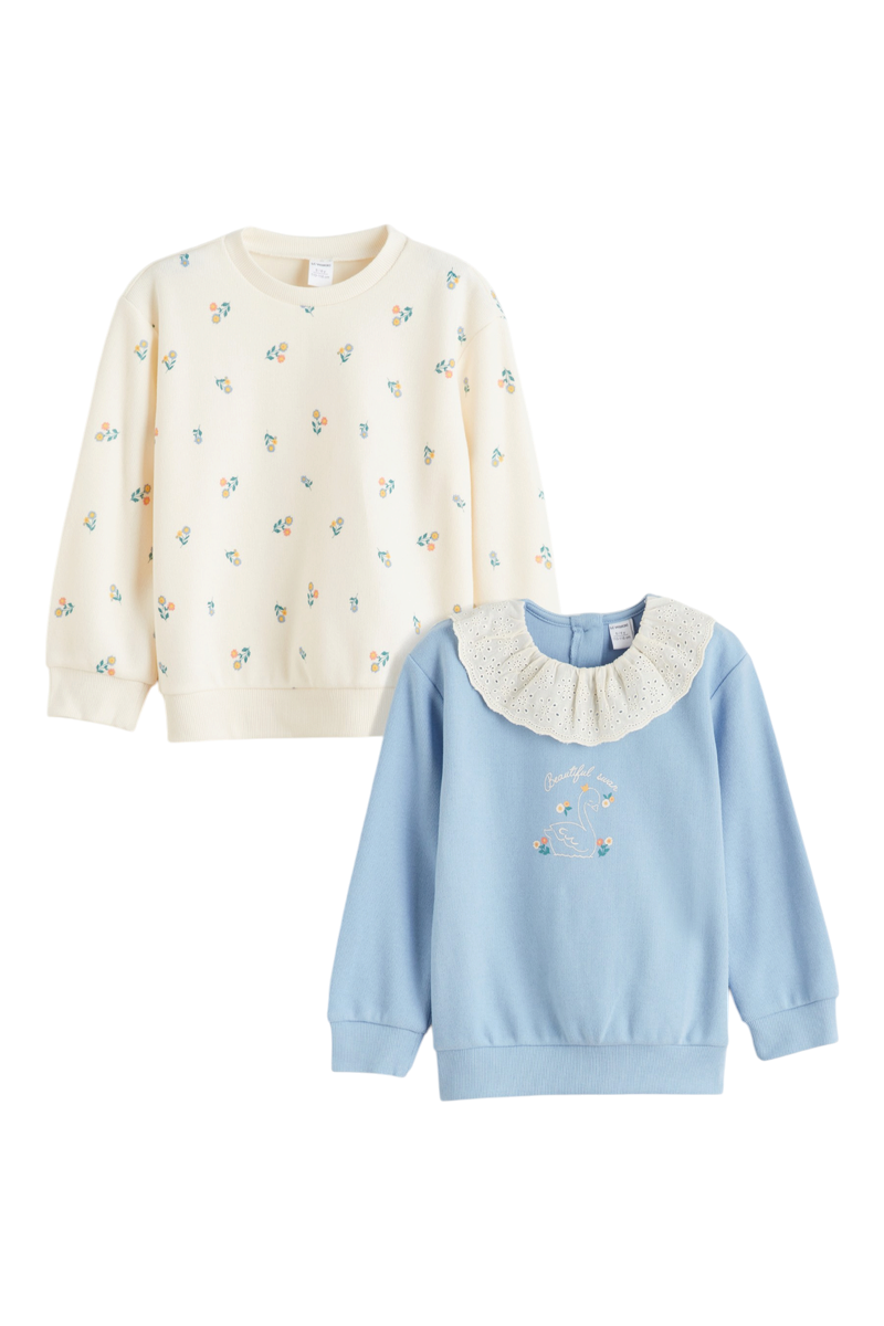 Sporline marka, biri çiçek desenli krem, diğeri yakalı ve kuğu baskılı pastel mavi iki adet çocuk sweatshirt takımı.