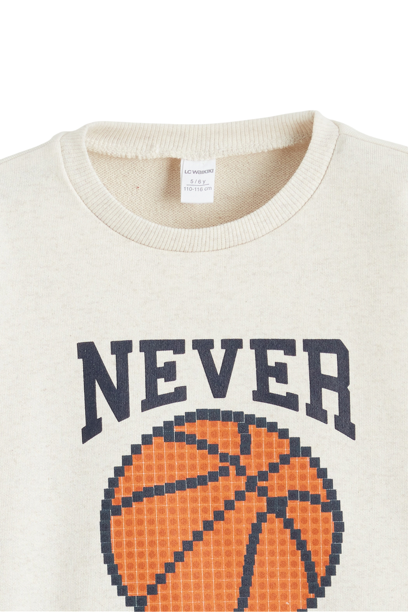 Sporline LC Waikiki kırık beyaz pamuklu çocuk sweatshirt, üzerinde basketbol topu ve NEVER yazılı baskı detayı.