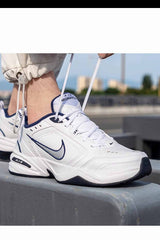 Sporline Nike Air Monarch IV beyaz ve gümüş detaylı erkek spor ayakkabı, bağcıkları bağlanırken yandan görünüm